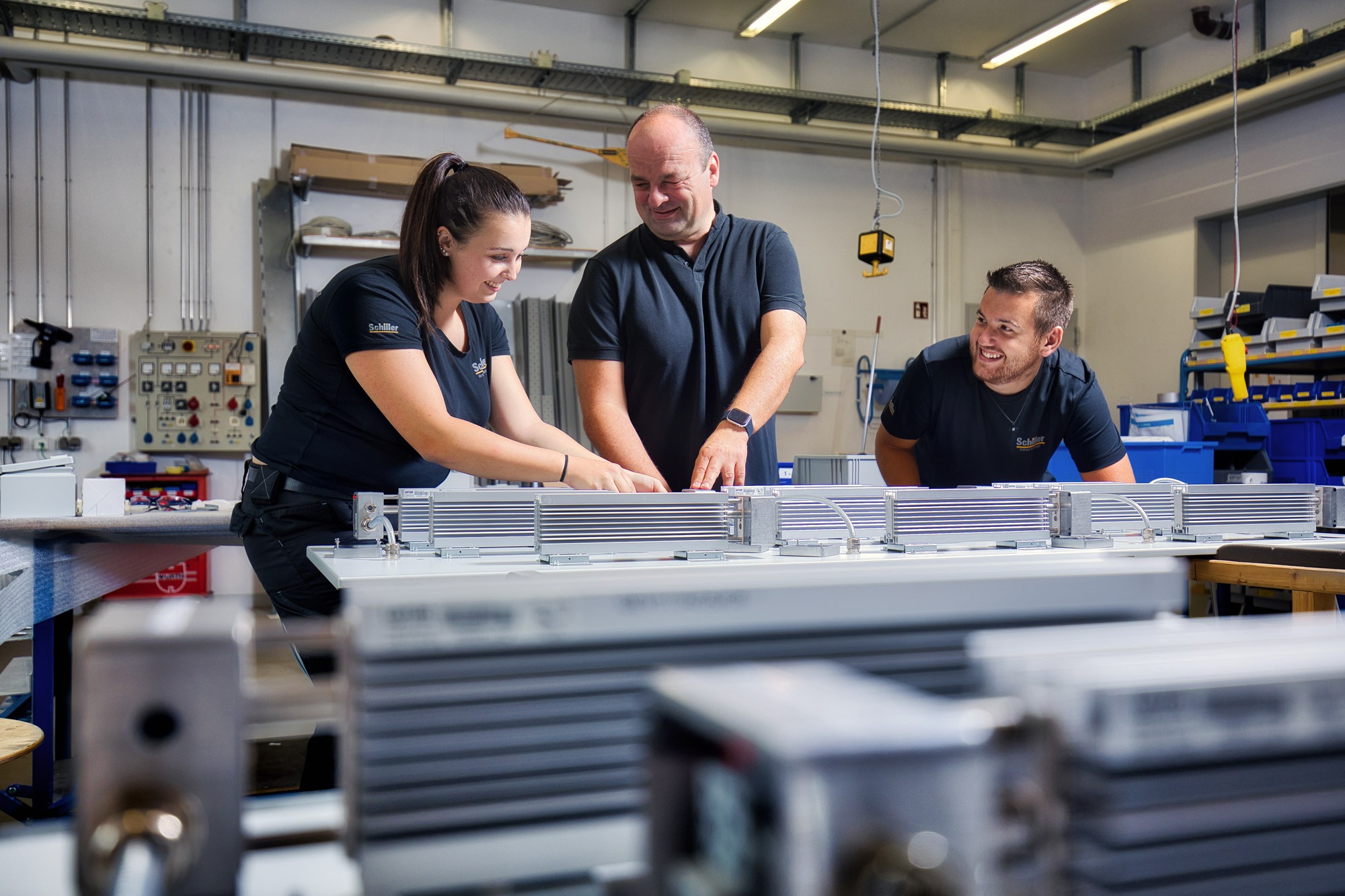 3 Elektroniker für Betriebstechnik arbeiten zusammen und lachen gemeinsam